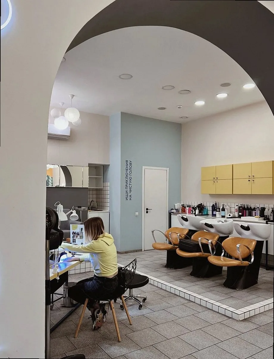 Contemporary hair salon interior featuring a customer seated at a styling station indoors.